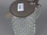 a glass pitcher with a metal lid on a table