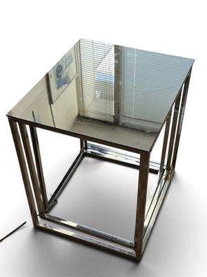 une table en verre avec une base en métal et un plateau en verre