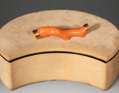 une boîte en bois munie d'une poignée orange, posée sur une surface grise