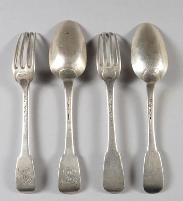 quatre cuillères en argent et une fourchette sont alignées sur une surface blanche