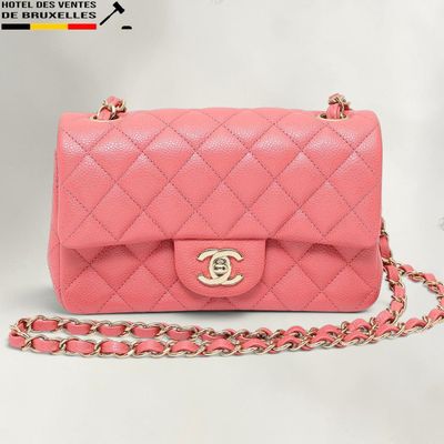 un sac Chanel rose avec une bandoulière en chaîne sur fond blanc
