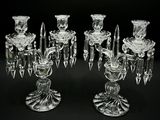 two clear glass candelabs with candles on a black background