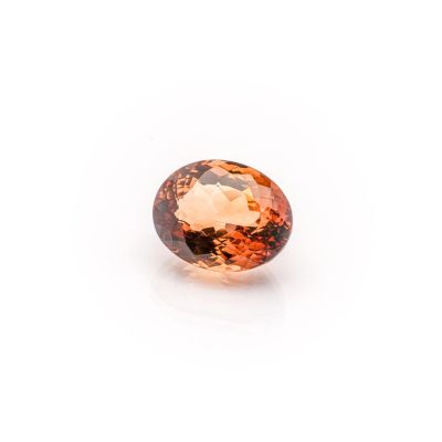 an oval faceted orange sapphire gems on a white background