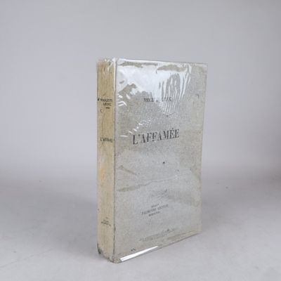 un vieux livre posé sur une table à côté d'un mur blanc