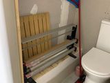des toilettes dans une petite salle de bains, avec des tuyaux et un siège de WC