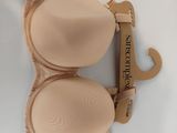 nude colored bras on display on a white surface with a wooden hanger