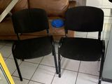 two black chairs sitting next to each other on a tiled floor