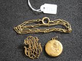 un gros plan sur un collier en or et deux breloques posés sur une surface noire