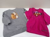 pair of children ' s sweatshirts with dogs on them sitting on a table
