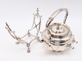 a silver tea pot and a silver tea kettle on a stand