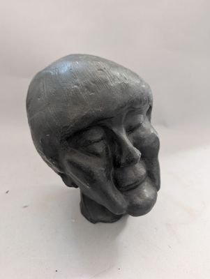 une sculpture représentant une tête d'homme sur une surface blanche