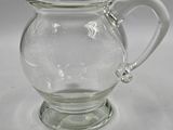 a clear glass pitcher with a handle on a table