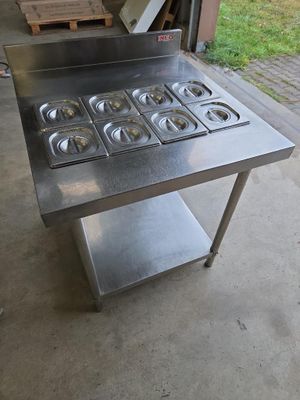 une table en acier inoxydable équipée de six brûleurs