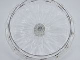 a close up of a clear glass cake plate with a silver rim