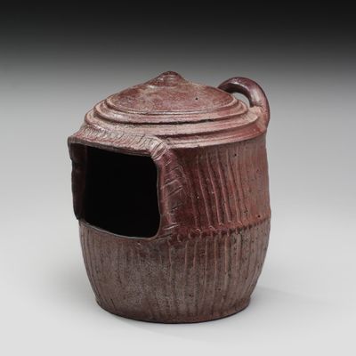 une image représentant un pot marron avec un couvercle, posé sur une surface blanche