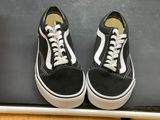 black and white old skool sneakers with white laces on top of a laptop