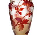 un vase en verre orné de fleurs rouges, posé sur une surface blanche