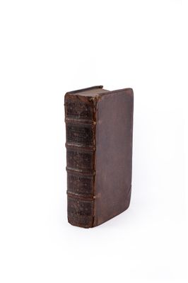 un vieux livre est posé sur une surface blanche avec un fond blanc