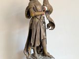 statue d'un homme tenant un oiseau, posée sur un socle posé sur une table