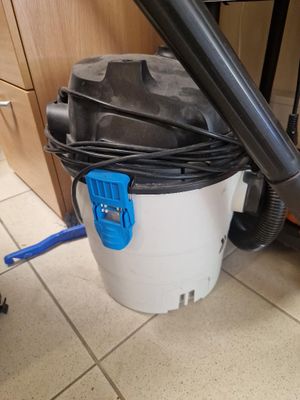 un aspirateur posé sur le sol à côté d'une poubelle