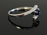 a close up of a diamond and sapphire ring on a black surface