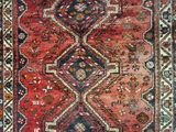 un vieux tapis persan orné d'un motif rouge et bleu