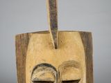 a close up of a wooden mask on a white surface