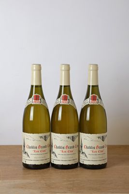 trois bouteilles de vin blanc posées sur une table en bois, à côté d'une bouteille de vin