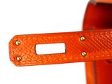 a close up of an orange bag with a metal handle