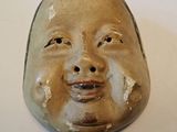 un masque en céramique représentant un visage, posé sur une table