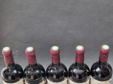 six bottles of wine are lined up in a row on a table