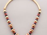 a gold necklace with multi colored beads on a white background