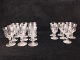 six clear glass goblets are lined up on a black surface
