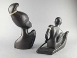 two statues of a man and a woman sitting on a chair