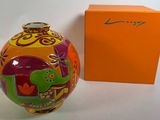 une image représentant un vase coloré posé à côté d'une boîte orange