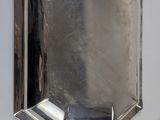 a silver plate with a mirror on it next to a spoon