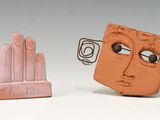 deux figurines en argile représentant un visage et une main