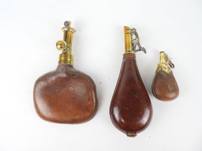 trois flacons de parfum anciens en laiton et en bois posés sur une surface blanche