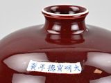 a red vase with writing on it sitting on a table