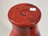 a red vase sitting on a table with a tag on it