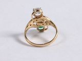 a close up of a gold ring with a diamond and a green stone