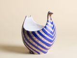 un petit vase bleu et blanc surmonté d'un oiseau
