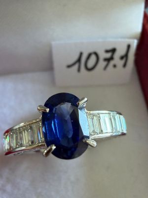 une photo d'une bague sertie d'un saphir bleu et de diamants, dans un écrin