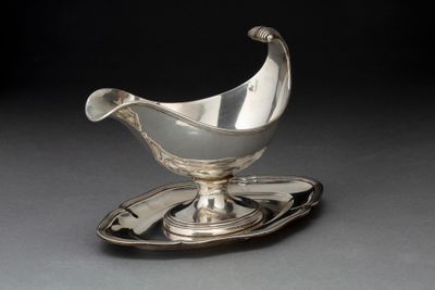 une assiette en argent sur laquelle repose une soucoupe en argent