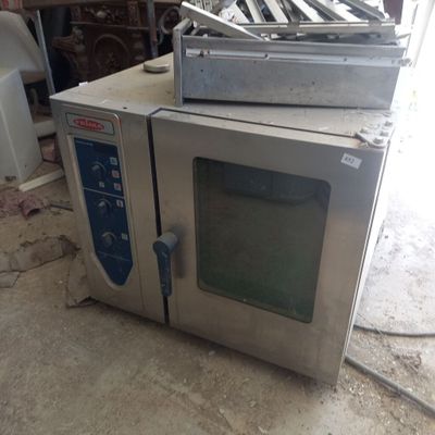 un four argenté posé sur un sol sale