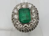 a close up of a ring with a green stone surrounded by white diamonds