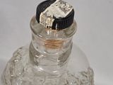 a clear glass bottle with a black lid on a white surface