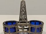 un bougeoir ancien en argent et en verre bleu posé sur une table blanche