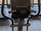 two tread machines in the gym with a view of the trees outside