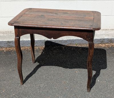 a small wooden table with a wooden top on the pavement